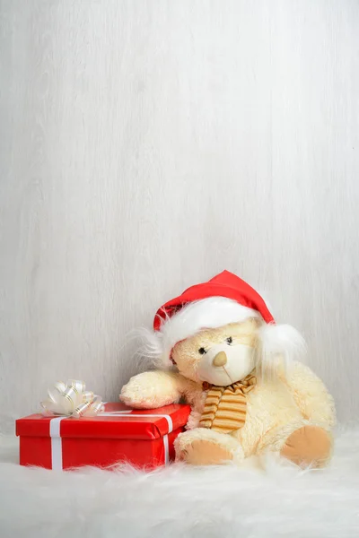 Teddy bear in kerstmuts met geschenken — Stockfoto