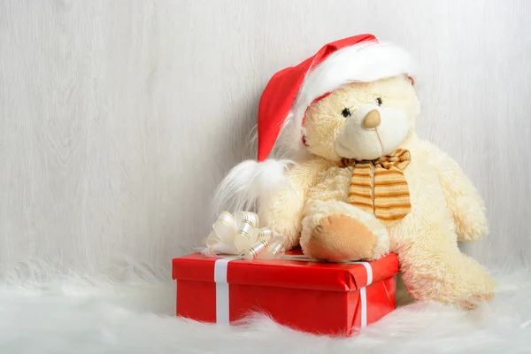 Teddy bear in kerstmuts met geschenken — Stockfoto