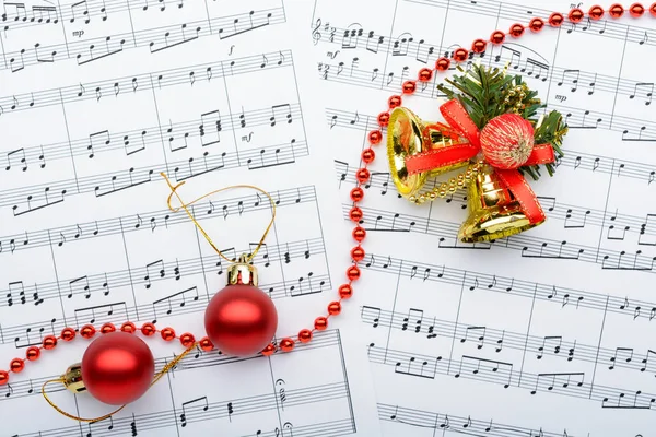 Christmas decorations lying on notes sheet — Stock Photo, Image