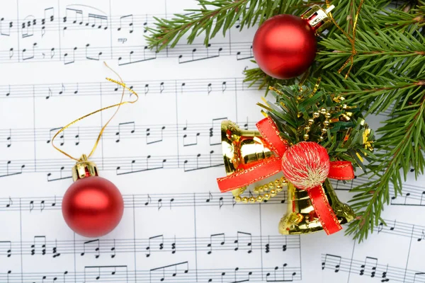 Christmas decorations lying on notes sheet — Stock Photo, Image