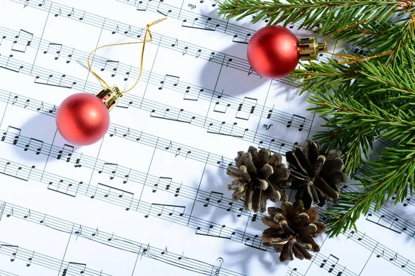 Christmas decorations lying on notes sheet — Stock Photo, Image