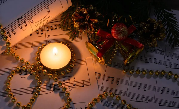 Kerstversiering, brandende kaars en bladmuziek — Stockfoto
