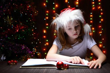 Bir kitap okuma Noel Baba şapkalı kız
