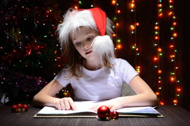 Bir kitap okuma Noel Baba şapkalı kız