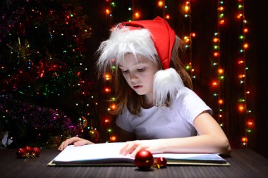 Bir kitap okuma Noel Baba şapkalı kız