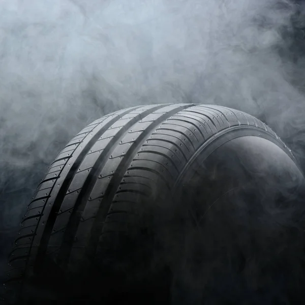 Car tire and smoke on black background