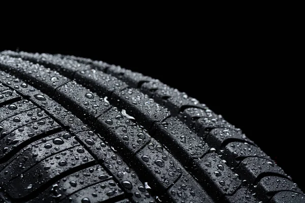 Automobilové pneumatiky pokryté vodou klesne na černém pozadí — Stock fotografie