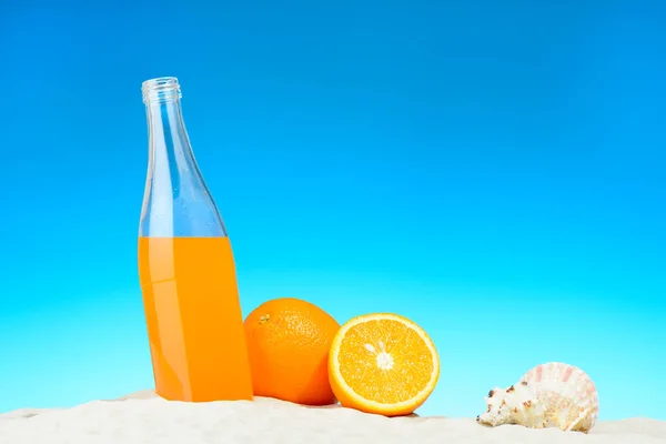 Butelka, sok pomarańczowy i owoce na plaży — Zdjęcie stockowe