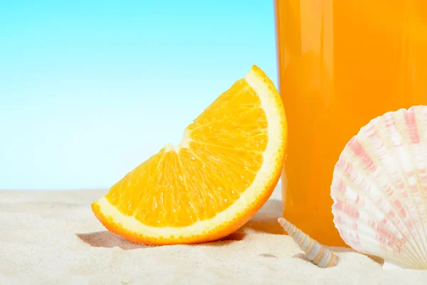 Sklenice pomerančové šťávy na pláži — Stock fotografie