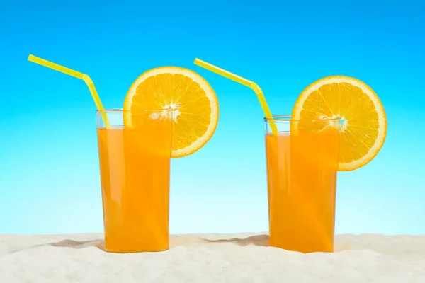 Dos vasos de jugo de naranja en la playa —  Fotos de Stock