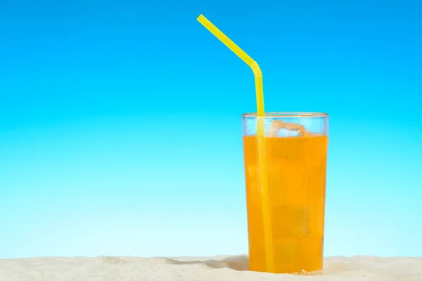 Un vaso de zumo de naranja con hielo en la playa —  Fotos de Stock