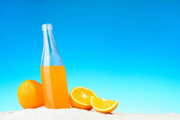 La botella de zumo de naranja y frutas en la playa —  Fotos de Stock