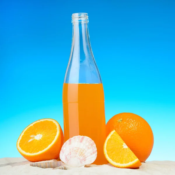 Láhev pomerančové šťávy a ovoce na pláži — Stock fotografie