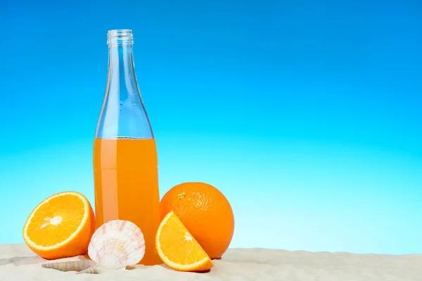 Бутылка апельсинового сока и фрукты на пляже — стоковое фото