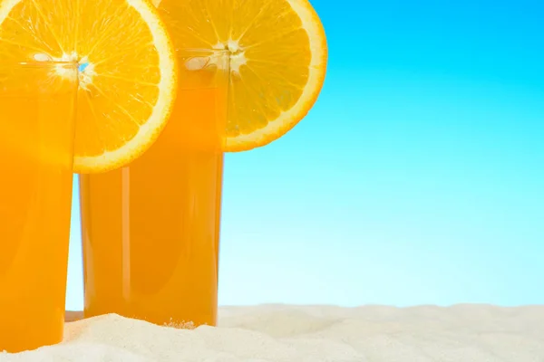 Dvě sklenice pomerančové šťávy na pláži — Stock fotografie