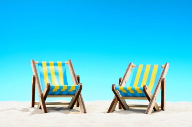 Mavi gökyüzü arka plan üzerinde sahilde iki şezlong