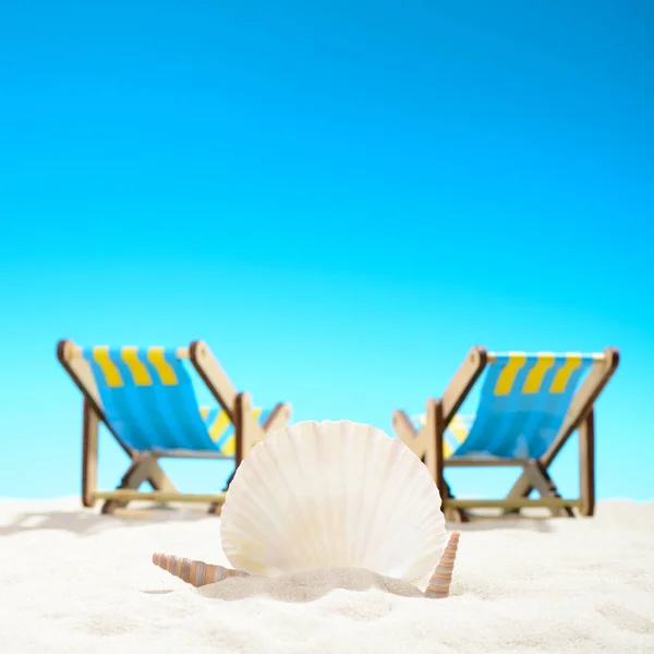 Seashell y dos tumbonas en la playa en el fondo del cielo azul — Foto de Stock