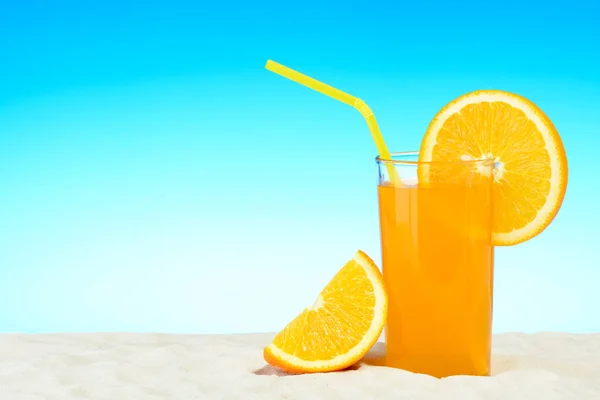 Стакан апельсинового сока на пляже — стоковое фото