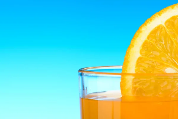 Un verre de jus d'orange sur fond bleu — Photo