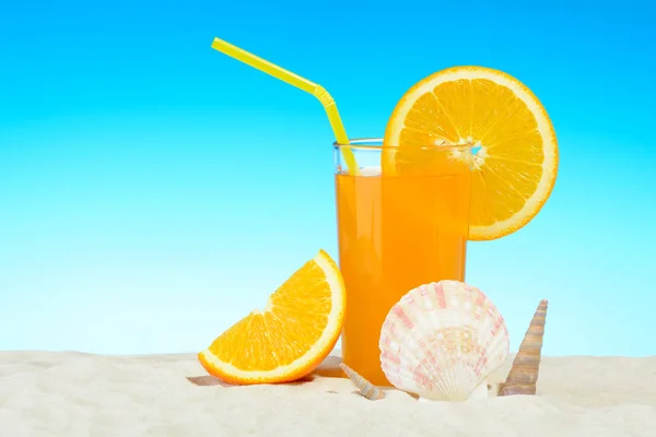 Un vaso de jugo de naranja en la playa —  Fotos de Stock