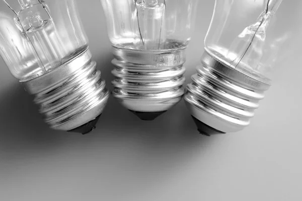 Tre lampadine ad incandescenza su fondo grigio — Foto Stock