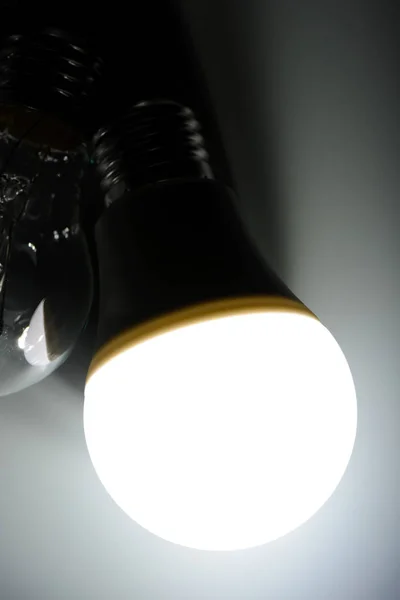 Светящаяся светодиодная лампа и лампа накаливания в темноте — стоковое фото
