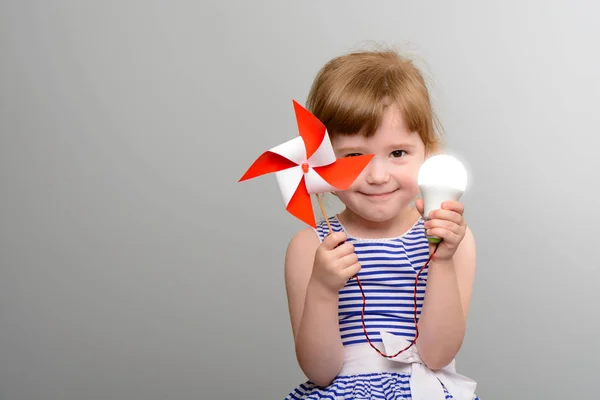Pojęcie energii odnawialnej. Ładna dziewczyna z led żarówki i wiatrak — Zdjęcie stockowe