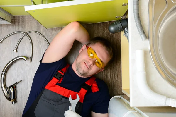 Plumber in the kitchen repairing the water pipe: top view