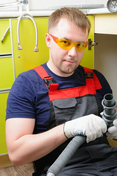 Plumber in the kitchen repairing the water pipe