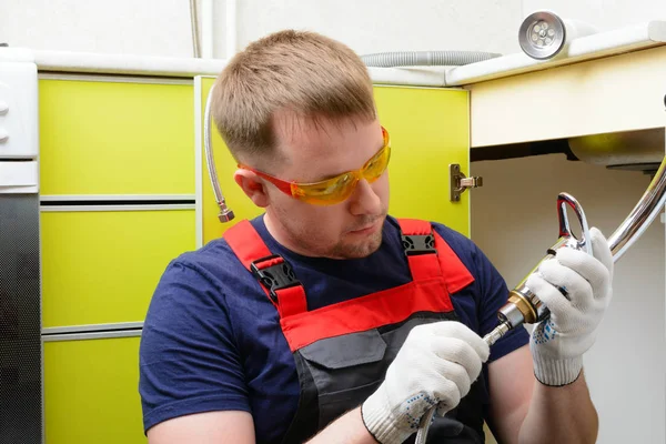 Plumber in the kitchen repairing the water pipe