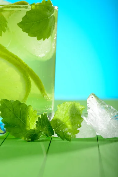 Un vaso de Mojito con hielo, limas y menta sobre tablas de madera —  Fotos de Stock