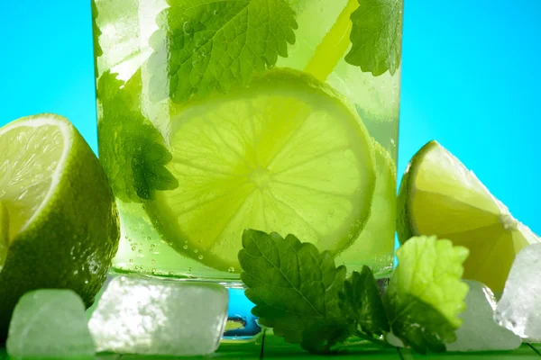 Un vaso de Mojito con hielo, limas y menta sobre tablas de madera —  Fotos de Stock