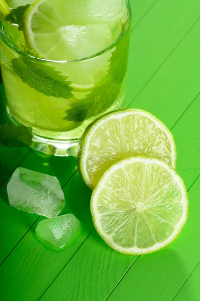 Ein Glas Mojito mit Eis, Limetten und Minze auf Holzbrettern — Stockfoto