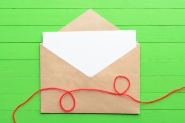 Yeşil ahşap arka plan üzerinde zarf ile boş kağıda