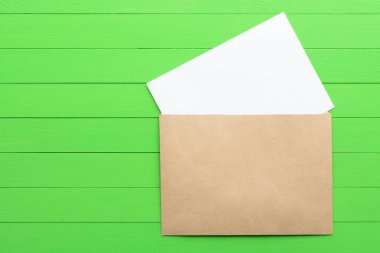 Yeşil ahşap arka plan üzerinde zarf ile boş kağıda