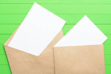 Yeşil ahşap arka plan üzerinde zarf ile boş kağıda