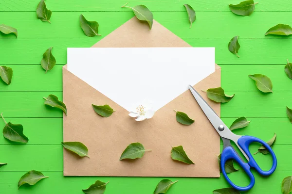 Un pedazo de papel en blanco con un sobre sobre sobre fondo de madera verde —  Fotos de Stock