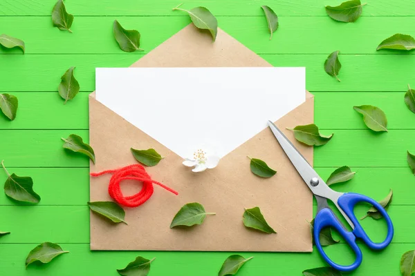 Un pezzo di carta bianco con una busta su sfondo di legno verde — Foto Stock