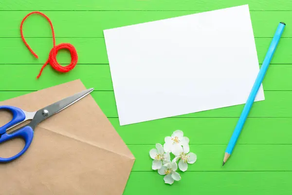 Ett tomt pappersark med ett kuvert på grön trä bakgrund — Stockfoto