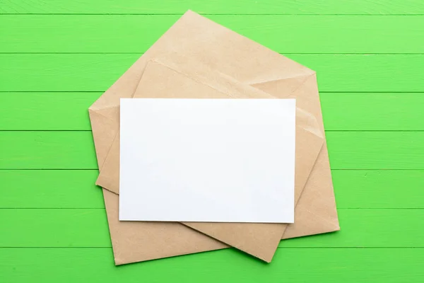 Pustej kartce papieru z koperty na zielonym tle drewnianych — Zdjęcie stockowe