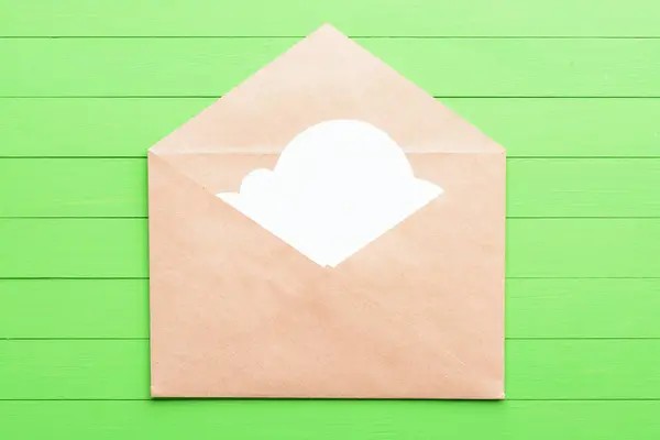 Adesivo bianco a forma di nuvole nella busta su sfondo di legno verde — Foto Stock