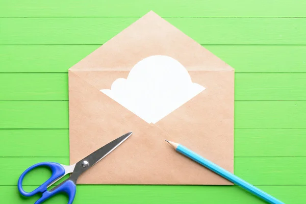 Белый наклейка в виде облаков в конверте на зеленом деревянном фоне — стоковое фото