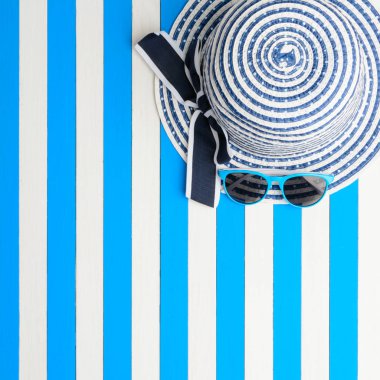 Çizgili şapka ve güneş gözlüğü mavi-beyaz arka plan üzerinde. Üstten Görünüm, düz yatıyordu.