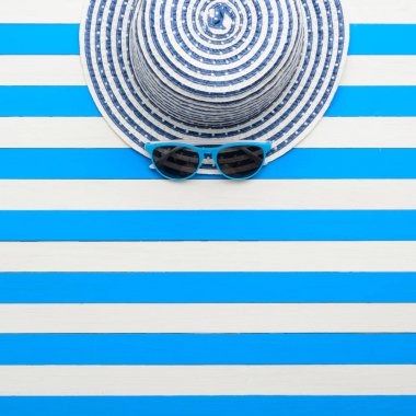 Çizgili şapka ve güneş gözlüğü mavi-beyaz arka plan üzerinde. Üstten Görünüm, düz yatıyordu.
