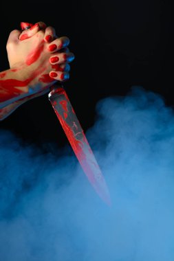 Kadın eli elinde kanlı bıçakla dumanlı arka planı kan