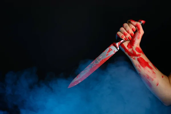 Mão de mulher de sangue segurando a faca sangrenta contra o fundo fumegante — Fotografia de Stock