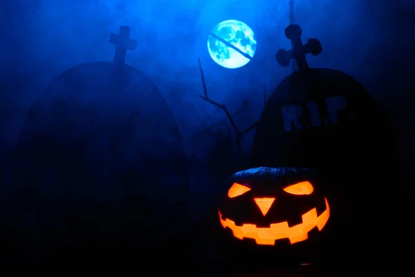 Spaventosa zucca di Halloween sullo sfondo di lapidi e luna piena nella nebbia — Foto Stock