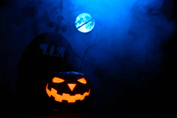 Spaventosa zucca di Halloween sullo sfondo di lapidi e luna piena nella nebbia — Foto Stock