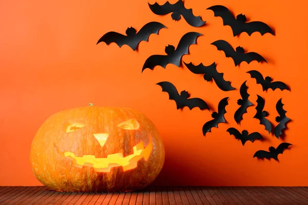 Parlayan Halloween pumpkins ve kağıt paketler bir turuncu duvar arka plan üzerinde yarasalar — Stok fotoğraf