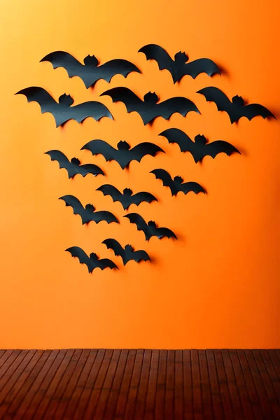 Стая бумажных летучих мышей на оранжевой стене — стоковое фото